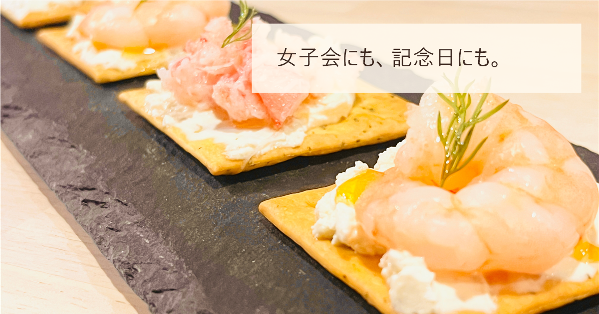 クラッカーに海老とカニをのせた前菜が並ぶ写真と「女子会にも、記念日にも。」の文字