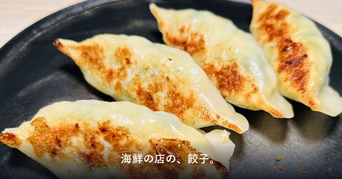 黒い皿に載った焼き餃子4個と「海鮮の店の、餃子。」の文字