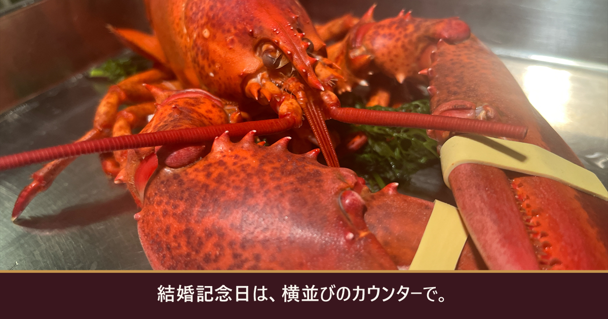 蒸し上がった活オマール海老と「結婚記念日は、横並びのカウンターで。」の文字