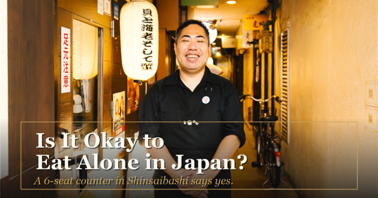 The owner of Kaiebi smiling outside the restaurant entrance under the shop's lantern, with the text Is It Okay to Eat Alone in Japan? A 6-seat counter in Shinsaibashi says yes.