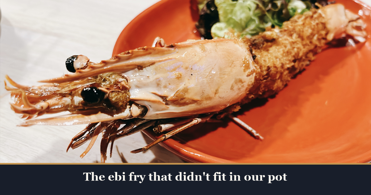 A giant head-on wild prawn ebi fry on an orange plate with salad leaves at Kaiebi, a 6-seat seafood counter in Shinsaibashi, Osaka