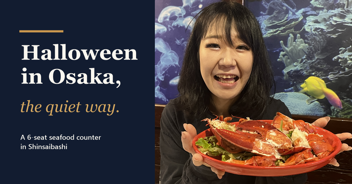 Mizuki-chan smiling and holding a red plate of lobster at our Shinsaibashi seafood counter, with the words Halloween in Osaka, the quiet way.