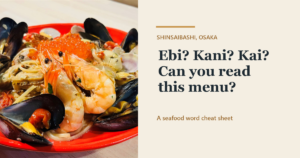 Seafood pasta with mussels, clams, prawns and salmon roe on a red plate, with the text "Ebi? Kani? Kai? Can you read this menu?" - Kaiebi, a 6-seat seafood counter in Shinsaibashi, Osaka