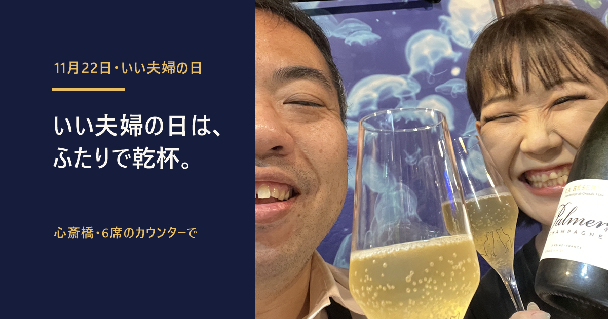 心斎橋「貝と海老そして蟹」の店内で、店主とみずきちゃんがシャンパンのグラスで乾杯する写真。「いい夫婦の日は、ふたりで乾杯。」の文字